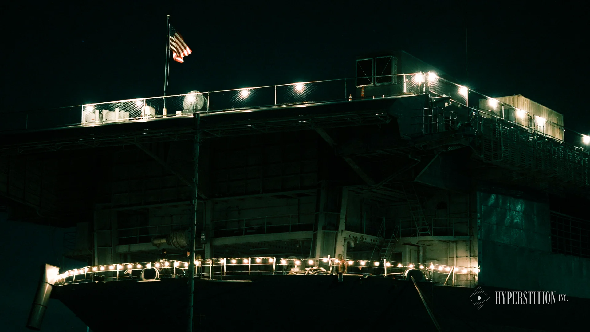 USS Hornet lit up at night, photographed during the 2024 hackathon